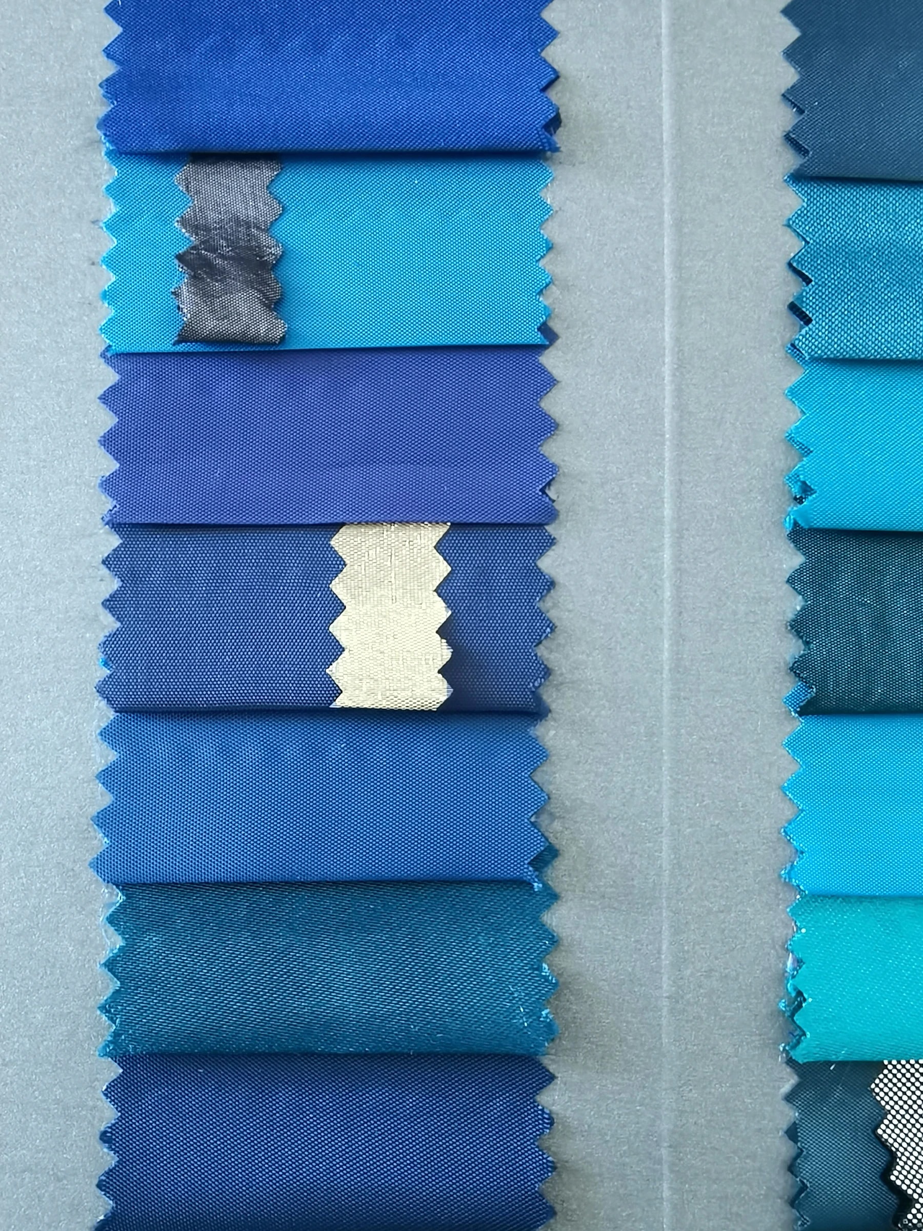 Fabric swatch book showing pinked samples of blue and teal uniform fabrics in various shades