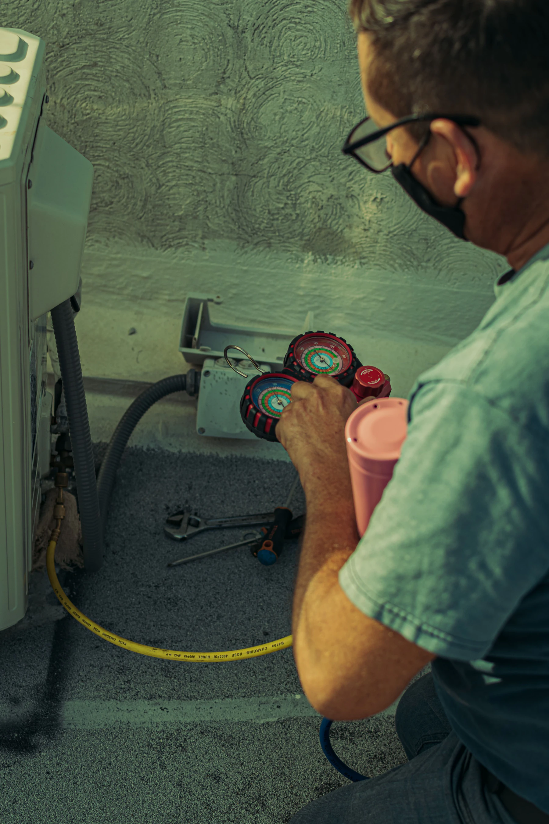 HVAC technician checking refrigerant pressure gauges while servicing an air conditioning unit